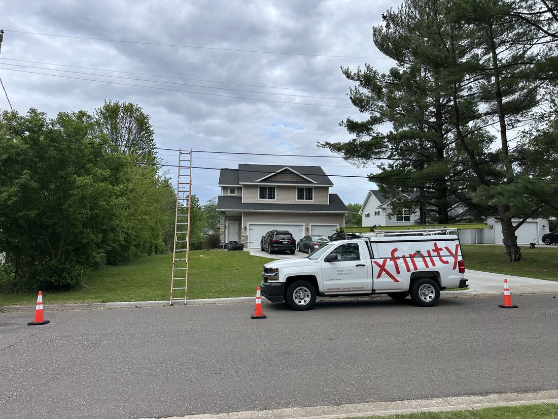 Branded truck with safety cones and ladder at a job